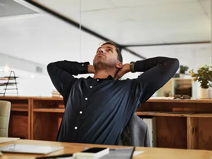 Office worker doing a gentle shoulder stretch at their desk